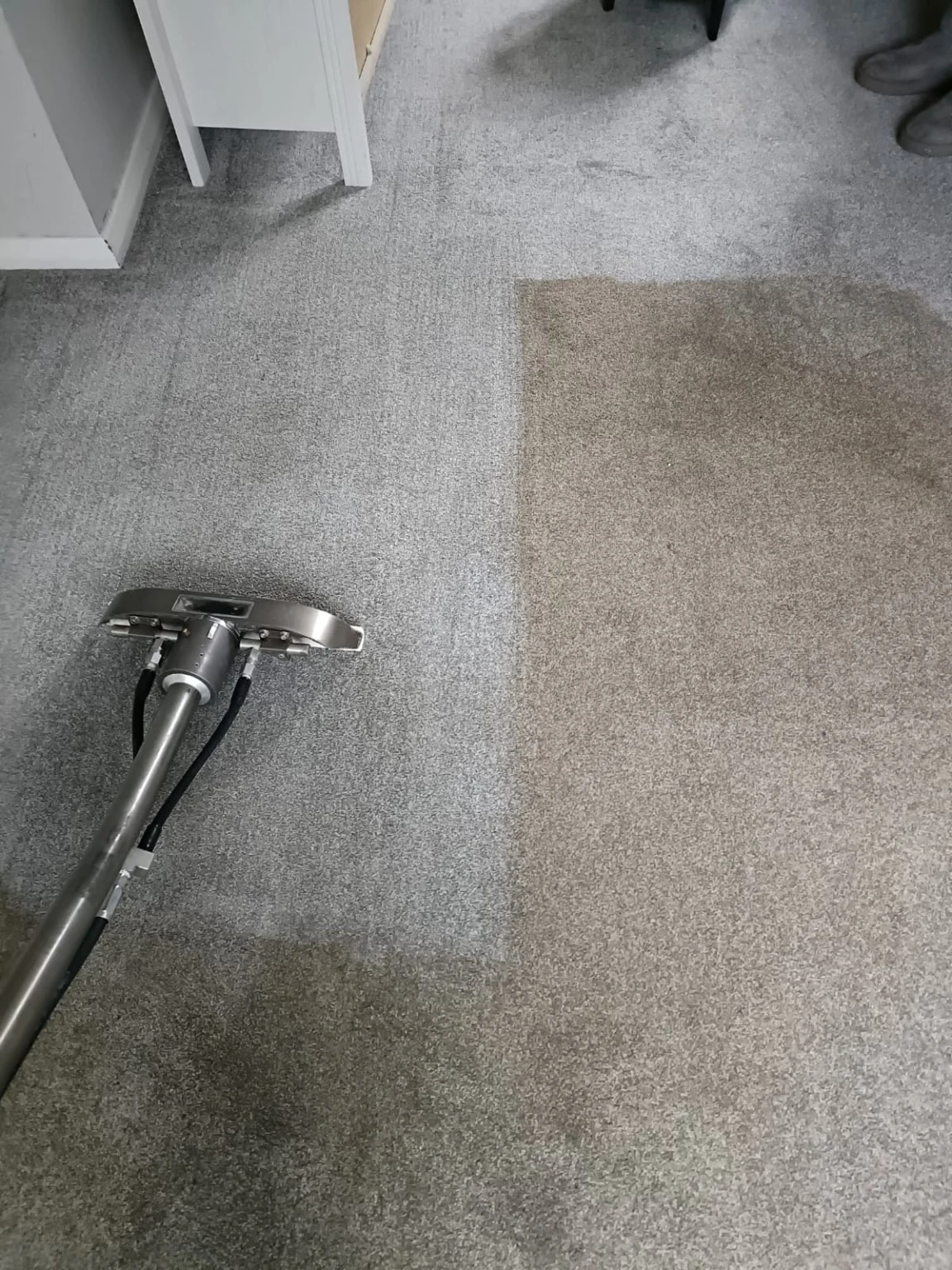 Extraction wand on grey carpet with visible cleaning passes